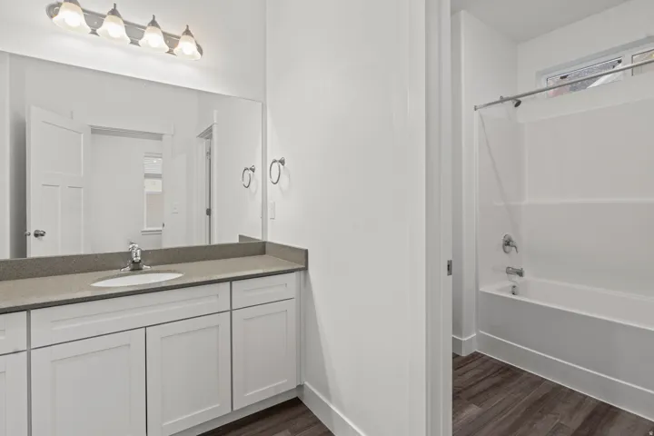 Bathroom with plenty of natural light, tub / shower combination, vanity, and dark wood finished floors
