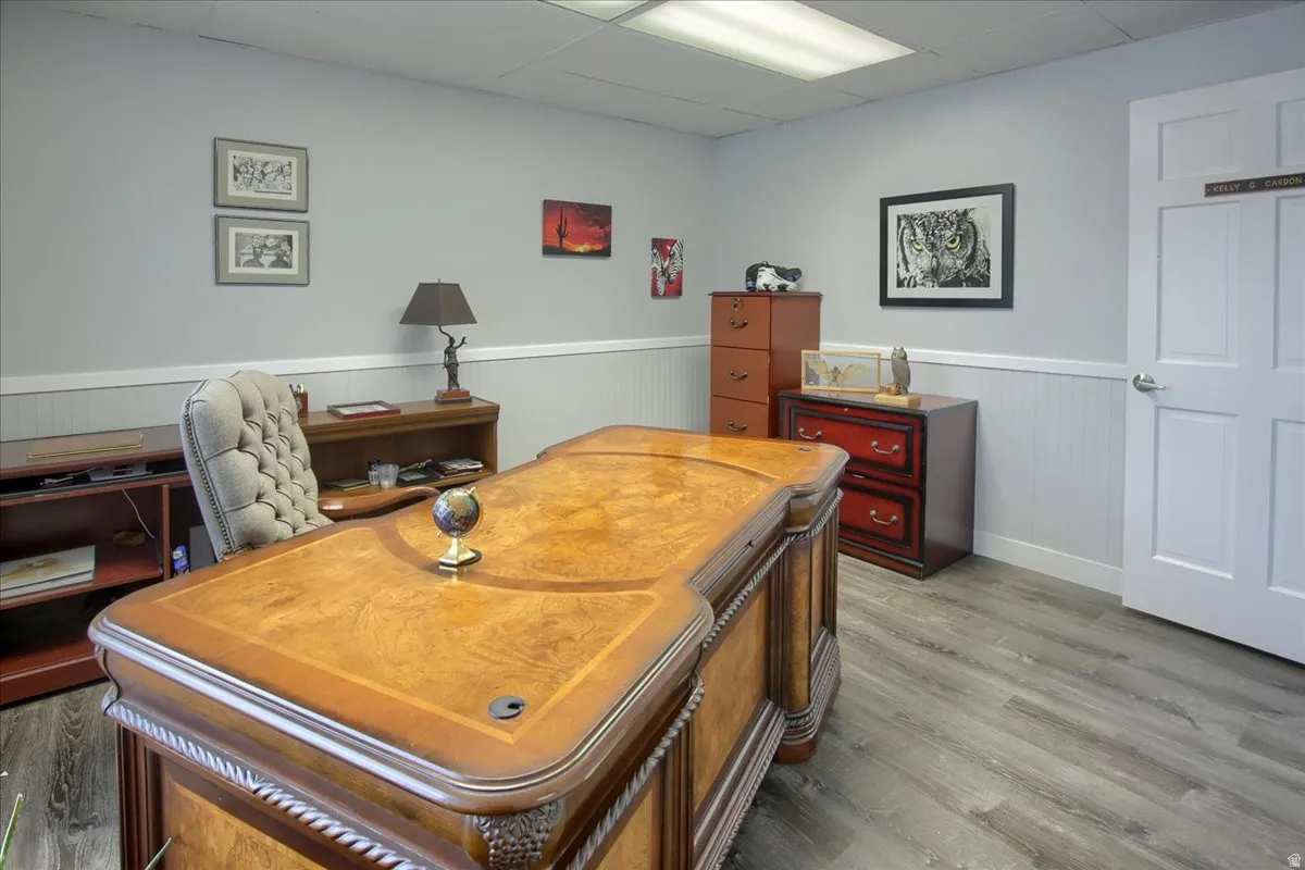Office area featuring a drop ceiling, wood finished floors, and wainscoting