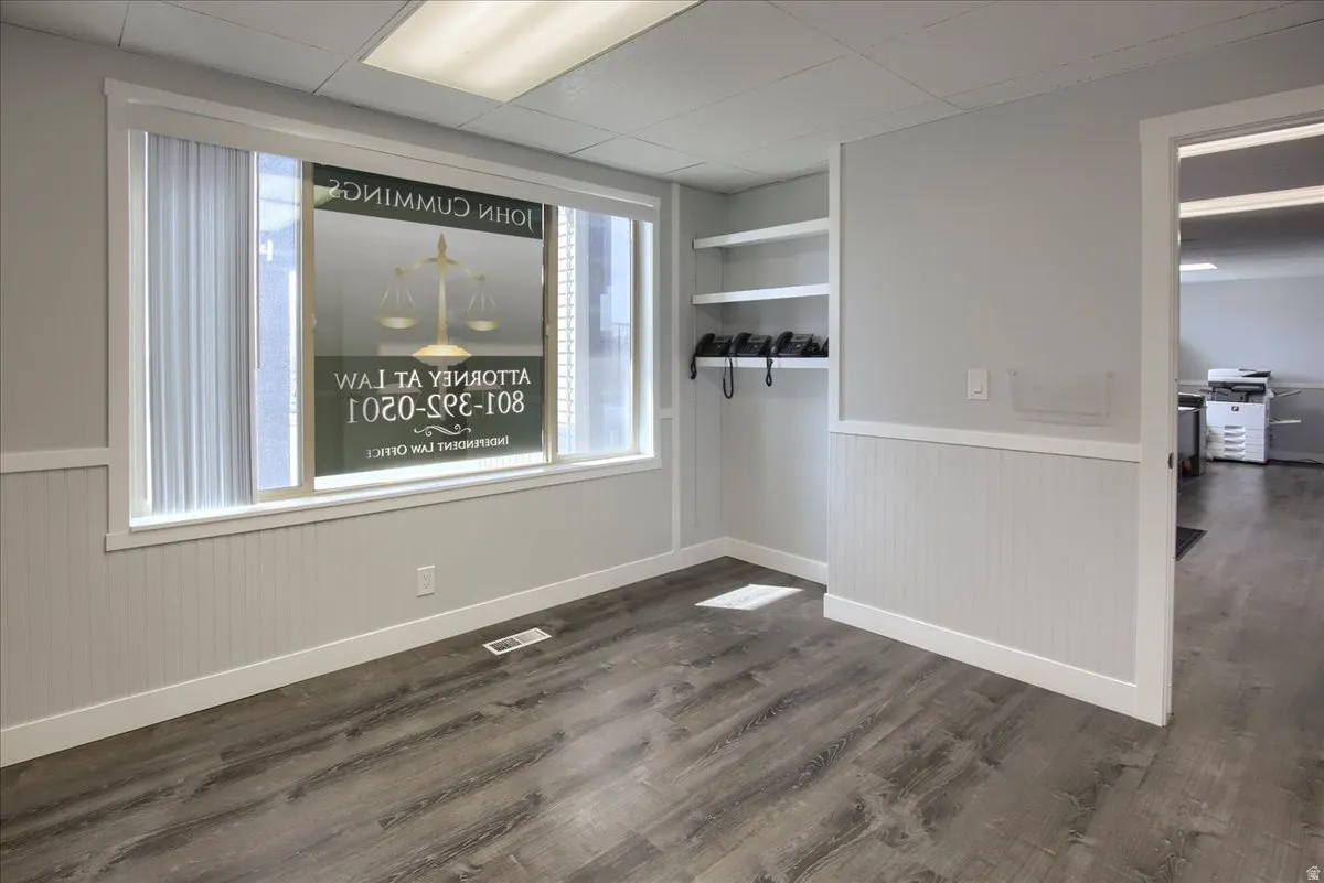 Spare room with dark wood finished floors, wainscoting, and a paneled ceiling