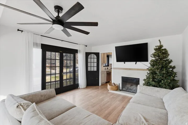 Living area featuring a glass covered fireplace, light wood-style flooring, and ceiling fan