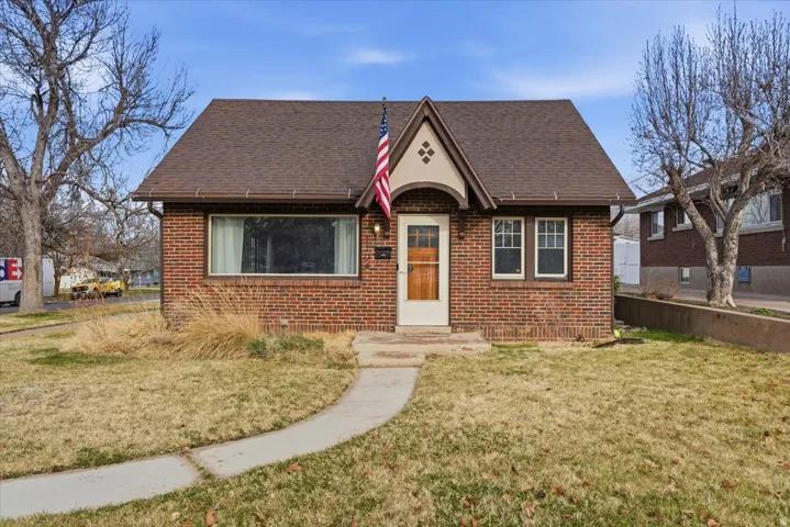 View of front of property featuring a front lawn, brick siding, and roof with shingles