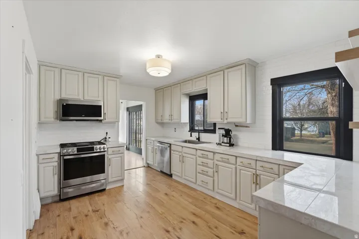 Kitchen featuring stainless steel appliances, light countertops, light wood-type flooring, and backsplash
