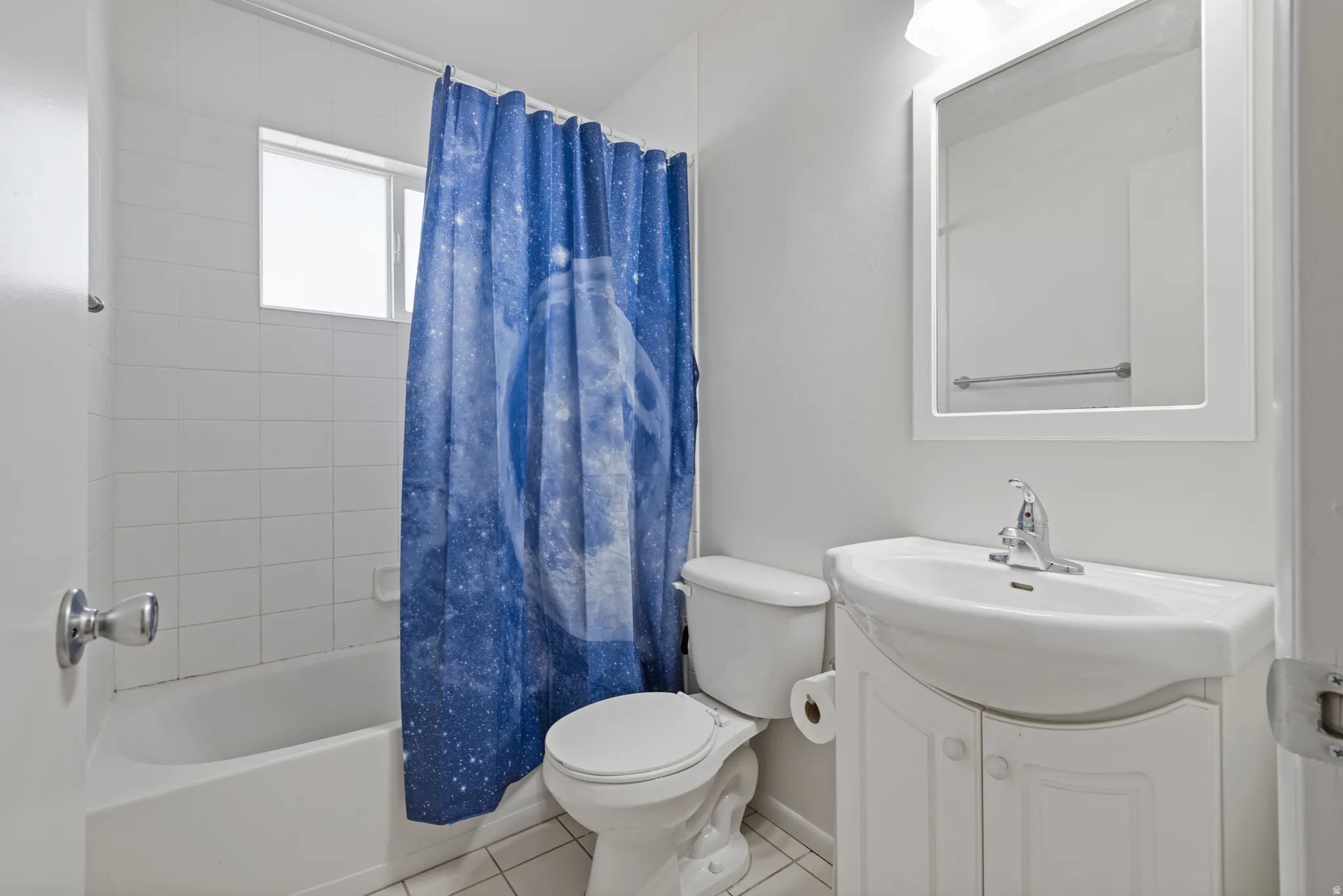 Full bath with tile patterned flooring, vanity, and shower / tub combo with curtain