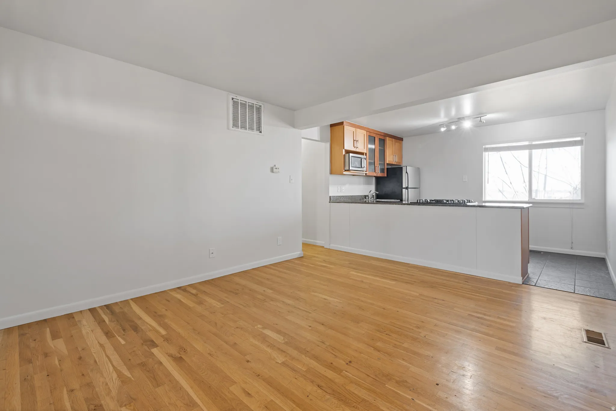 Unfurnished living room with light wood-type flooring and rail lighting