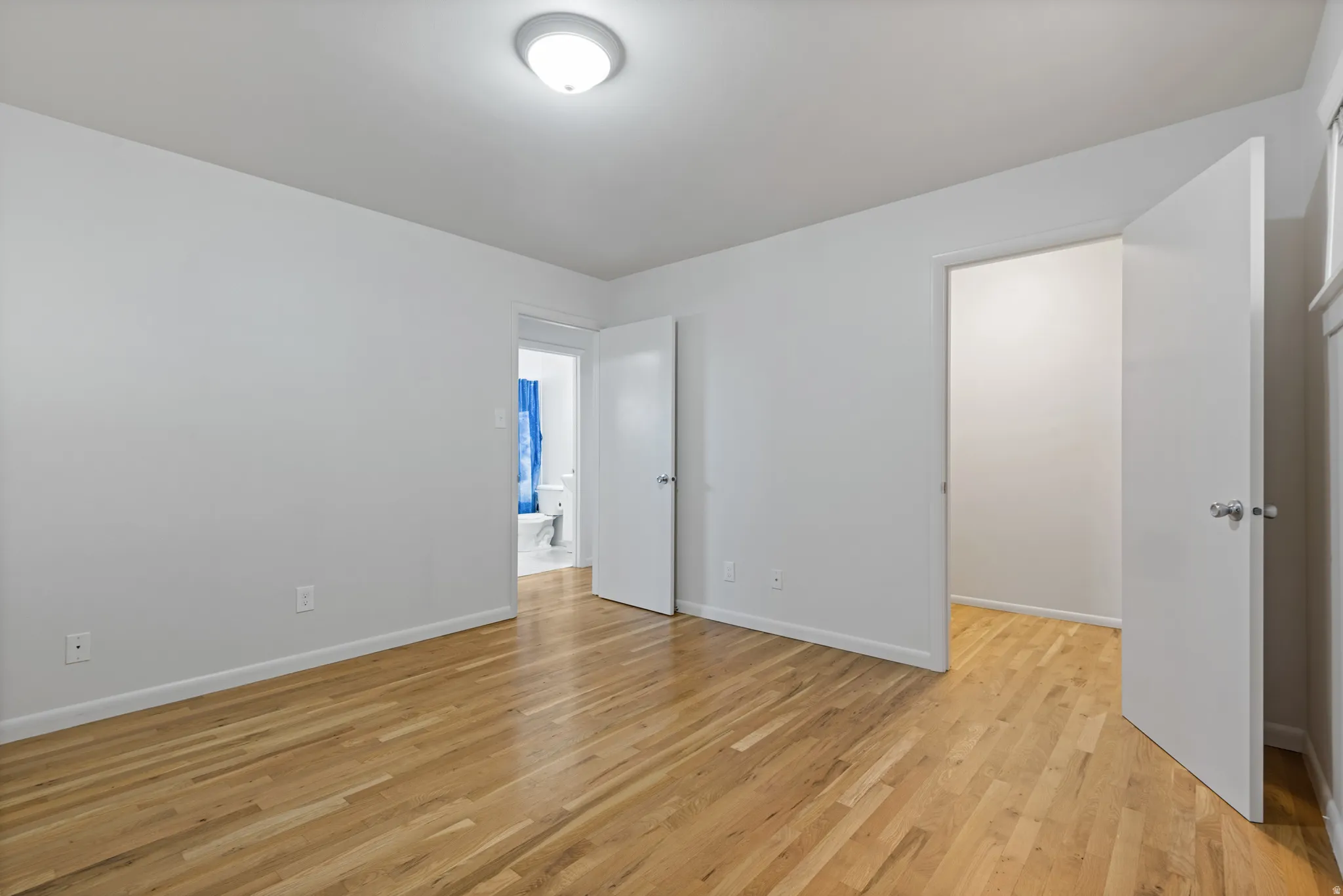Unfurnished bedroom featuring light wood finished floors and baseboards