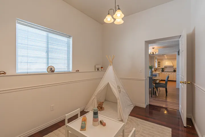 Playroom with a chandelier, dark wood-style floors, and vaulted ceiling
