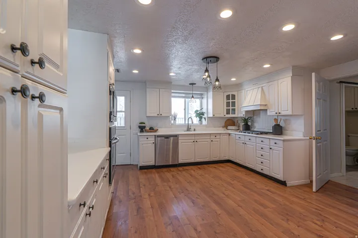 Kitchen featuring a textured ceiling, recessed lighting, hanging light fixtures, dark wood-type flooring, and stainless steel appliances