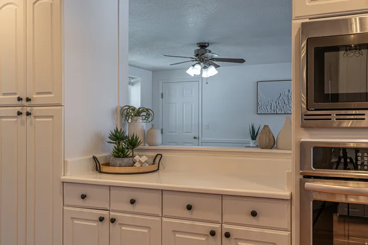 Kitchen featuring appliances with stainless steel finishes, light countertops, white cabinetry, a textured ceiling, and a ceiling fan