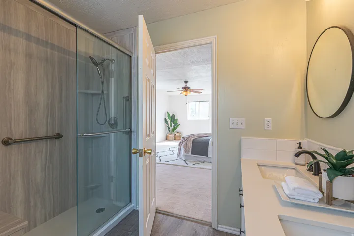 Full bath featuring a textured ceiling, vanity, a shower stall, ensuite bath, and dark colored carpet