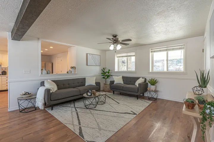 Living room featuring a wainscoted wall, a textured ceiling, ceiling fan, and hardwood / wood-style floors