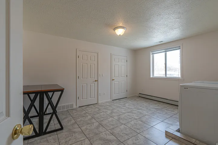 Laundry area with washer / clothes dryer, a textured ceiling, and a baseboard heating unit