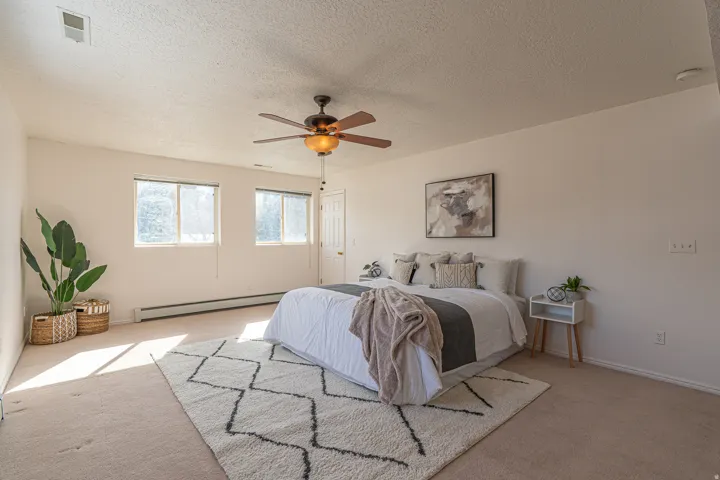 Carpeted bedroom featuring a textured ceiling, a baseboard radiator, and ceiling fan