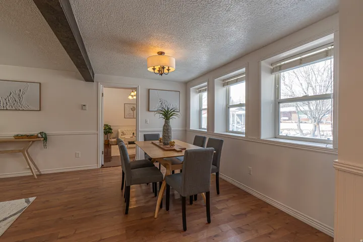 Dining area featuring hardwood / wood-style flooring, wainscoting, and a textured ceiling