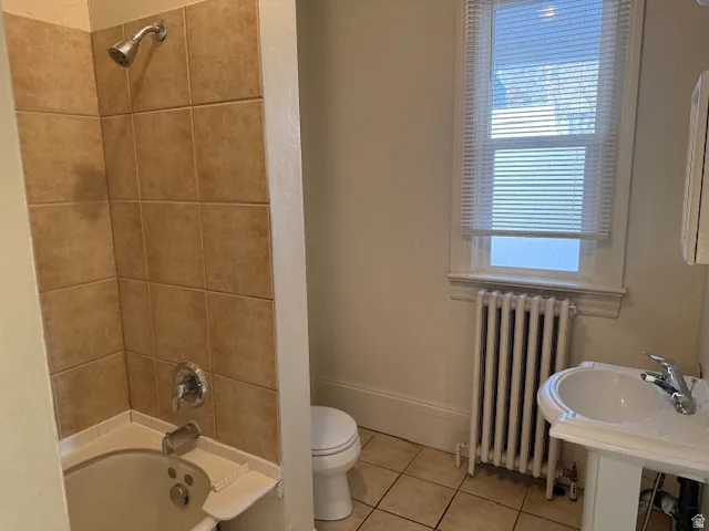 Bathroom with radiator heating unit, shower / bathtub combination, and tile patterned floors