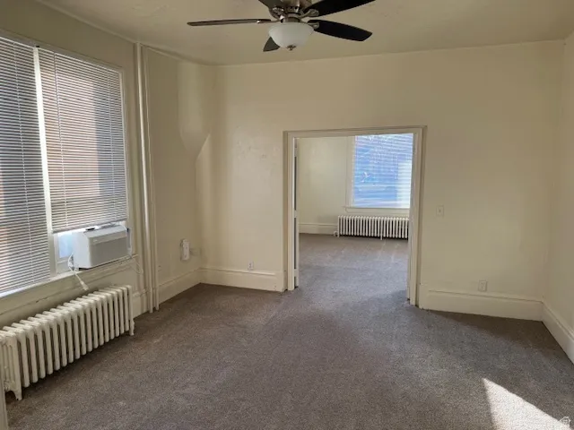 Carpeted spare room with radiator heating unit, cooling unit, and a ceiling fan