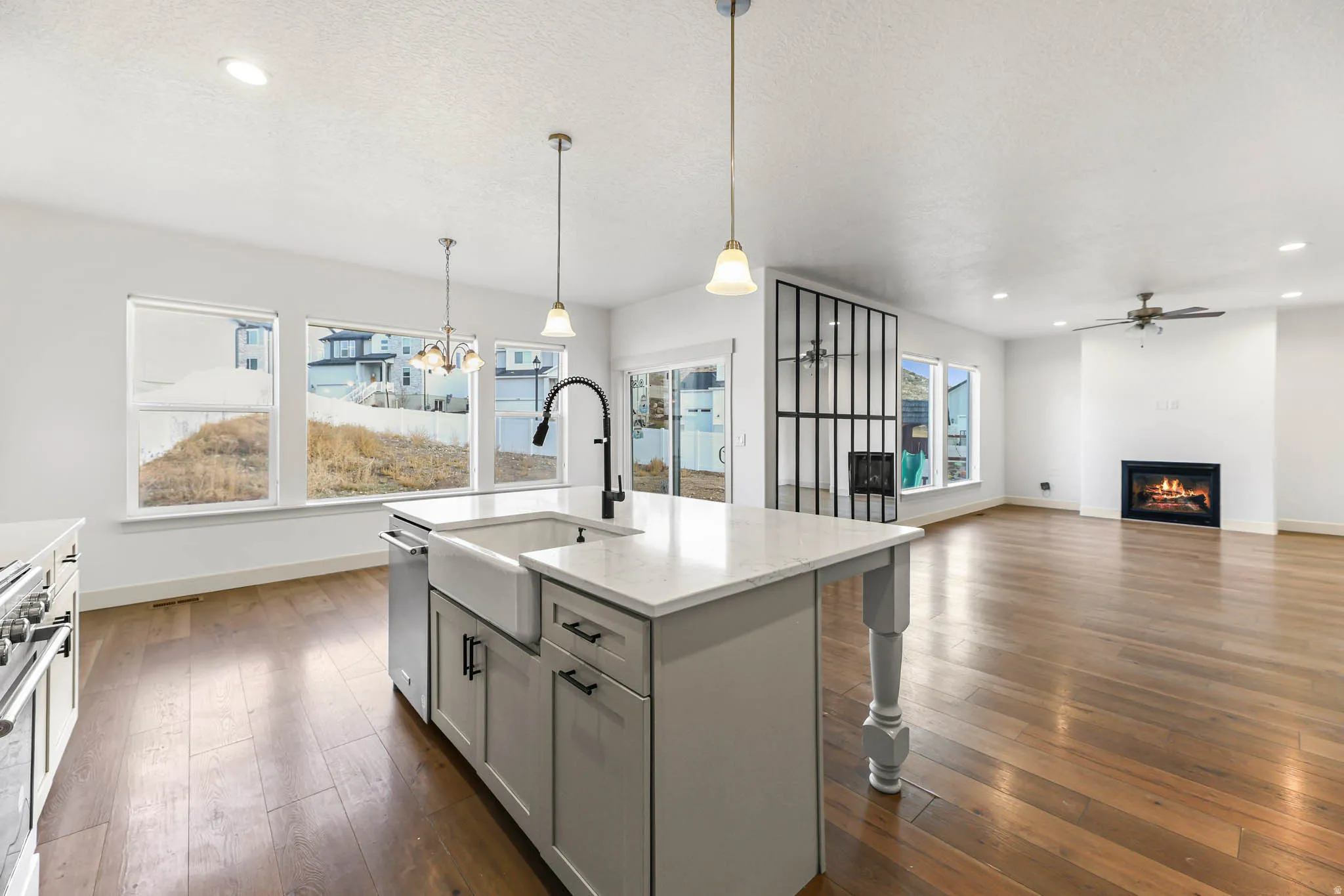 Kitchen featuring pendant lighting, open floor plan, a kitchen island with sink, light stone counters, and dark wood finished floors