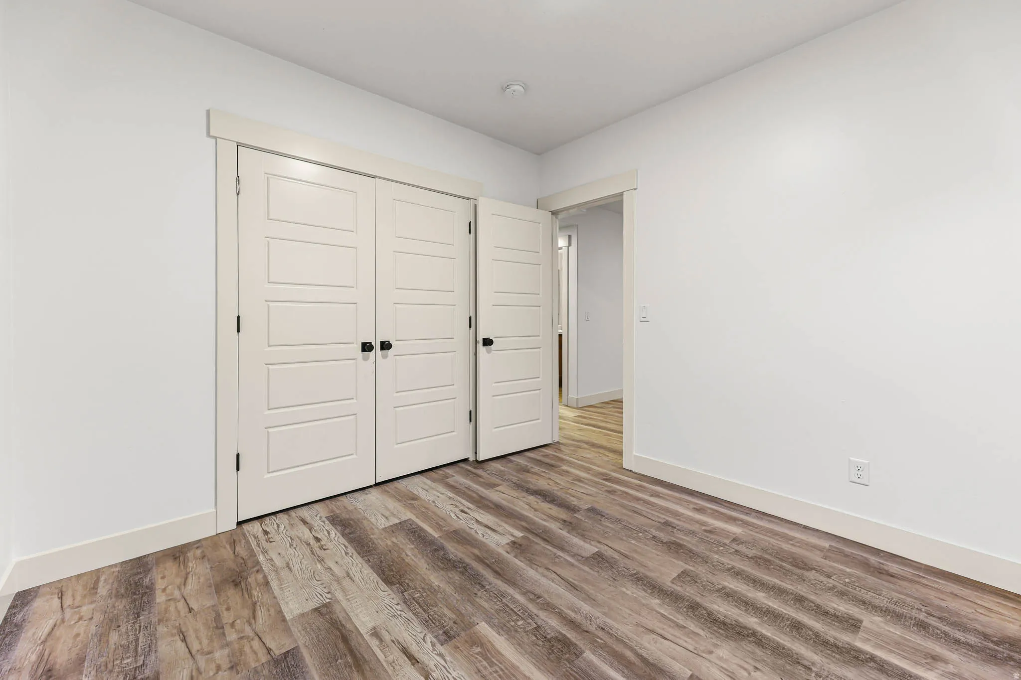 Unfurnished bedroom with wood finished floors and a closet