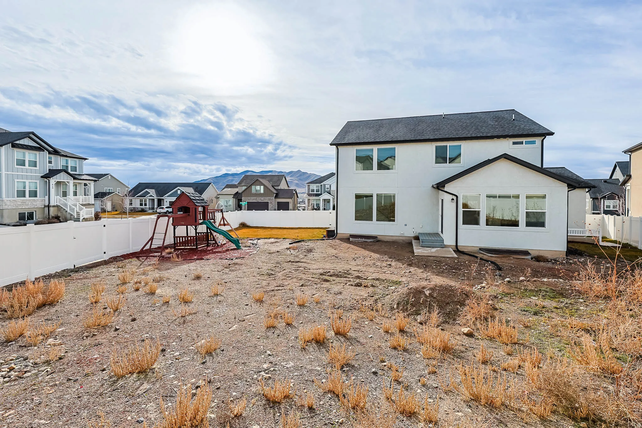 Back of house featuring a fenced backyard, a residential view, a playground, and stucco siding