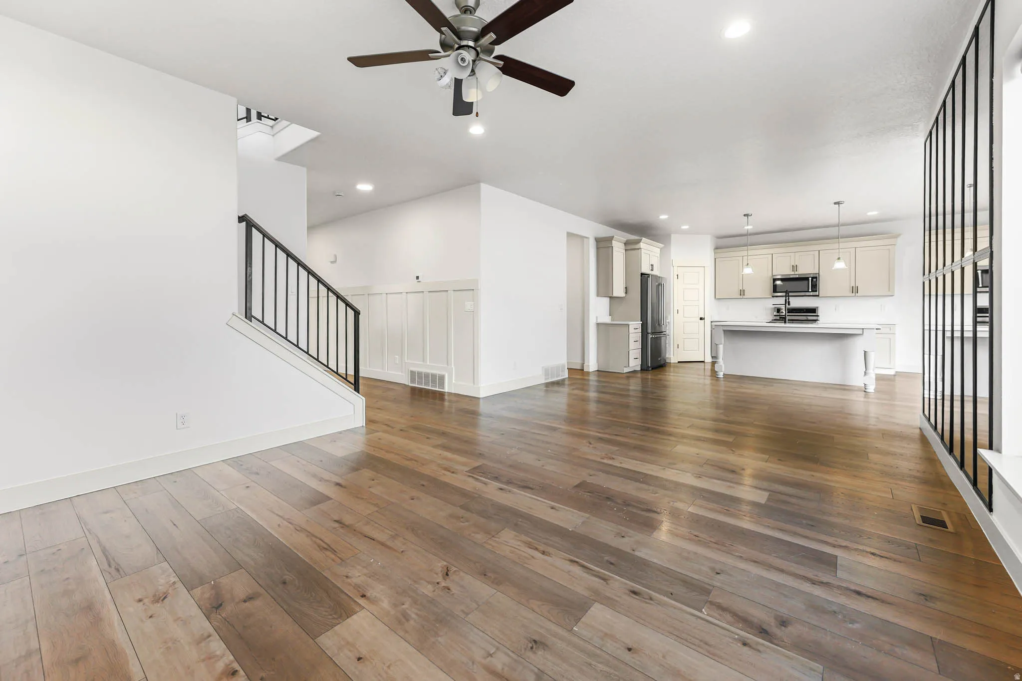 Unfurnished living room featuring stairs, dark wood finished floors, a ceiling fan, and recessed lighting