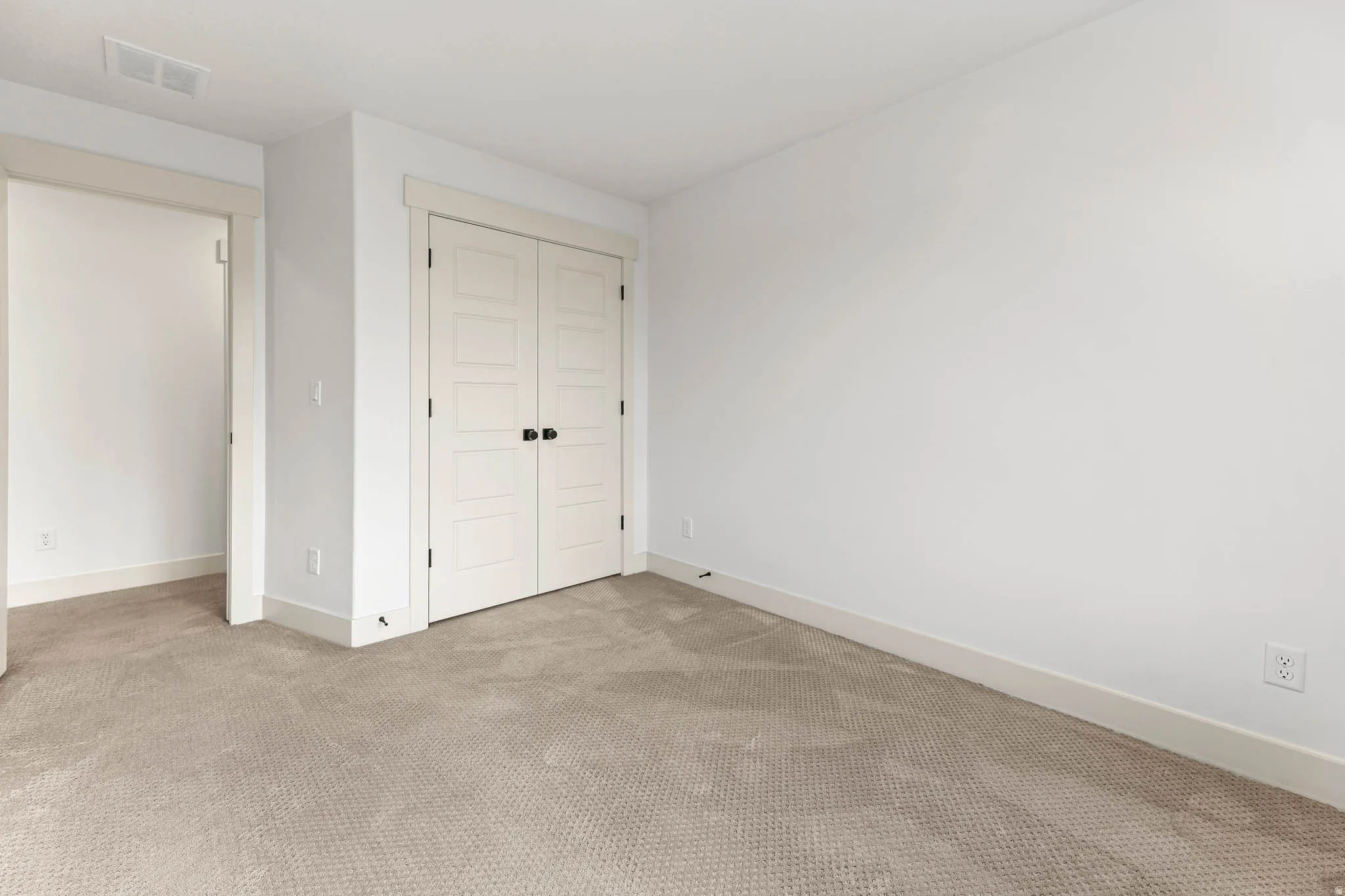 Unfurnished bedroom featuring light colored carpet and a closet
