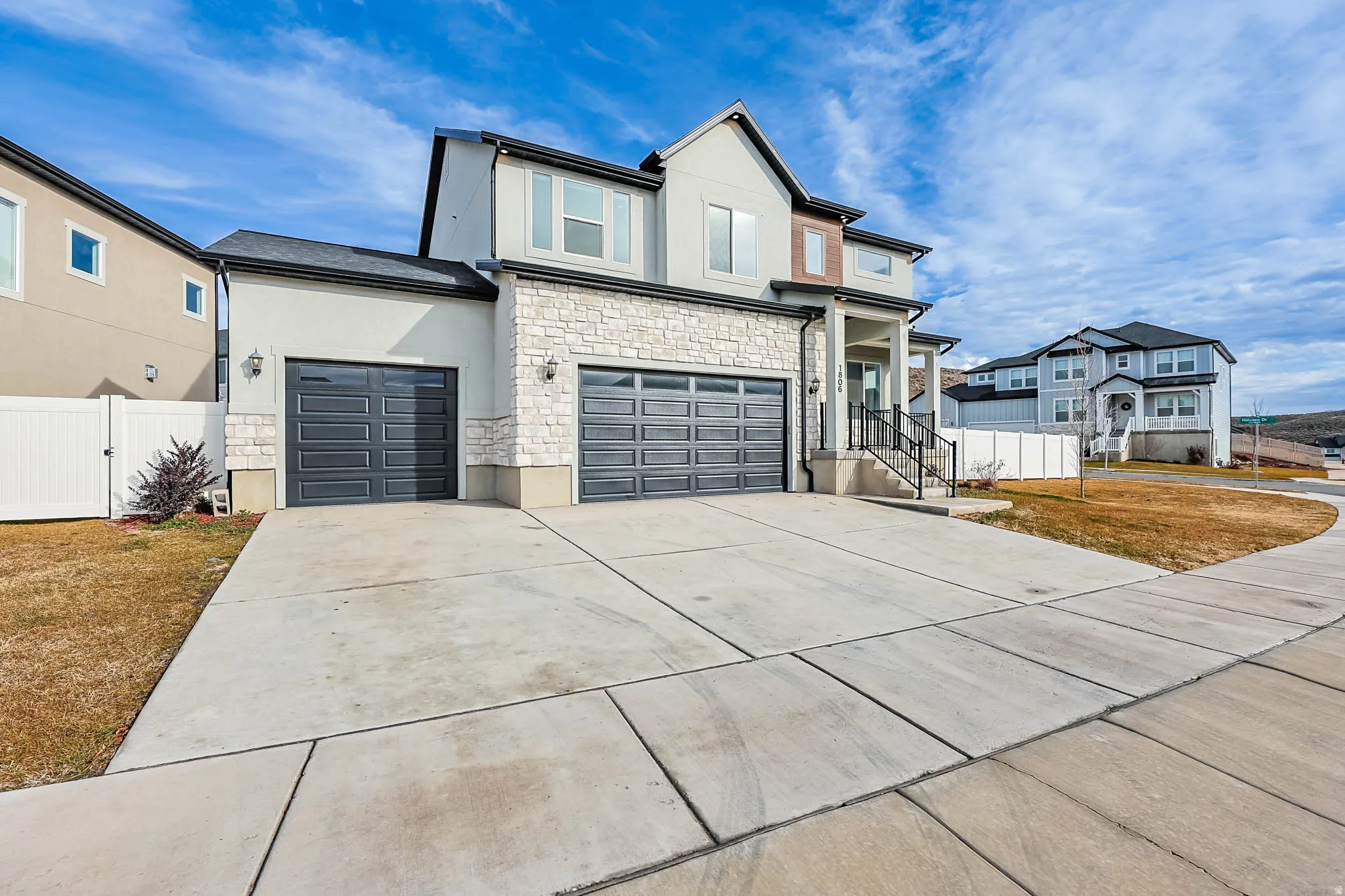 View of front of property featuring stone siding, stucco siding, concrete driveway, and a garage