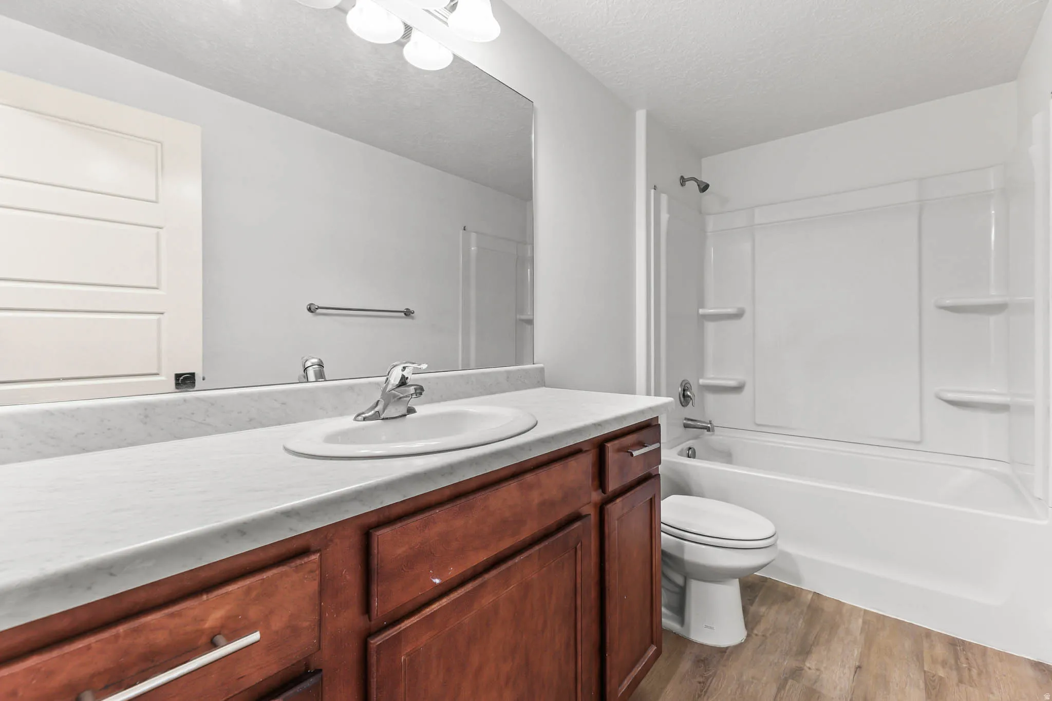 Bathroom with vanity, shower / bathtub combination, dark wood-style floors, and a textured ceiling