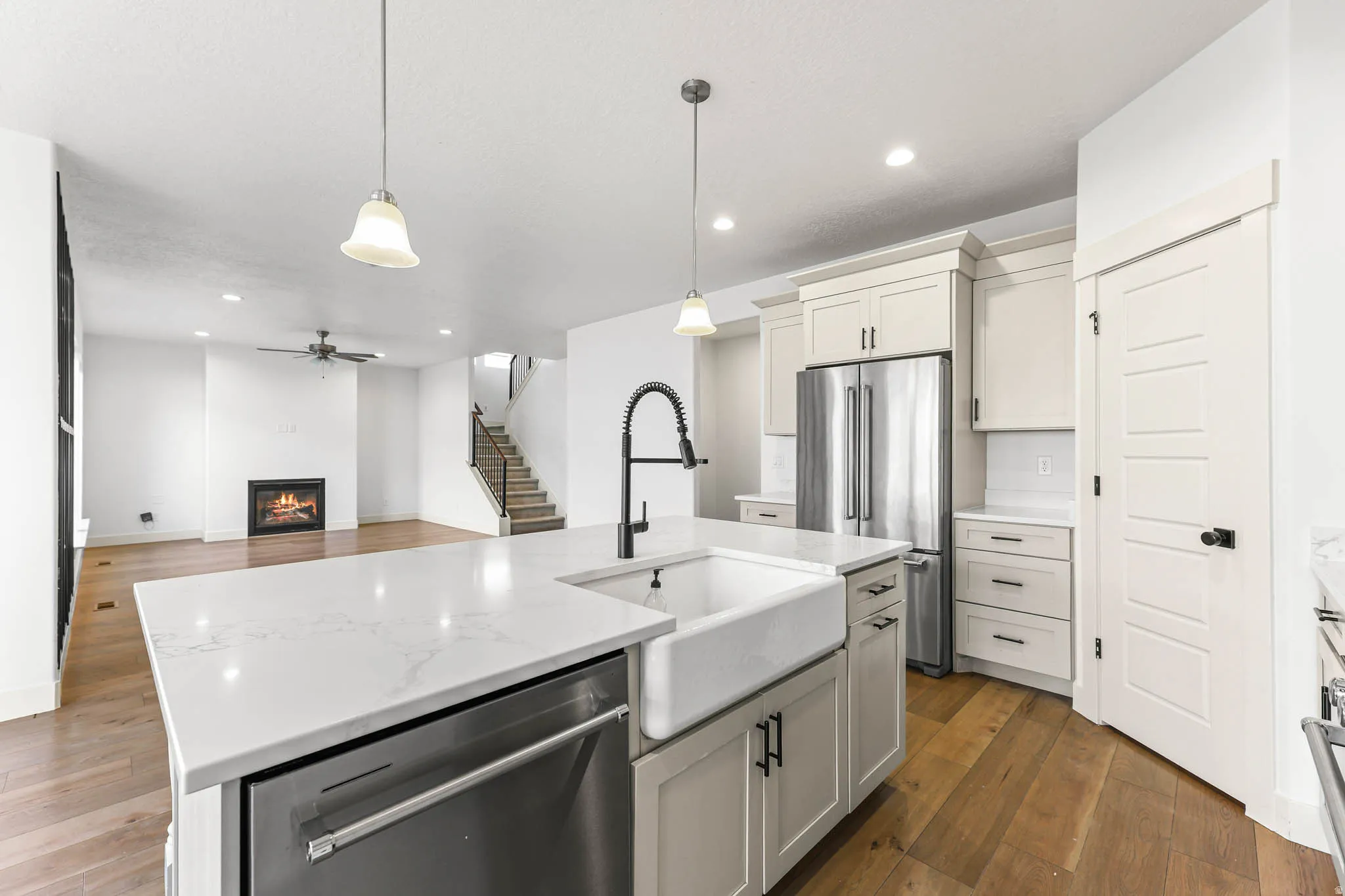 Kitchen with appliances with stainless steel finishes, decorative light fixtures, dark wood-style flooring, a warm lit fireplace, and recessed lighting