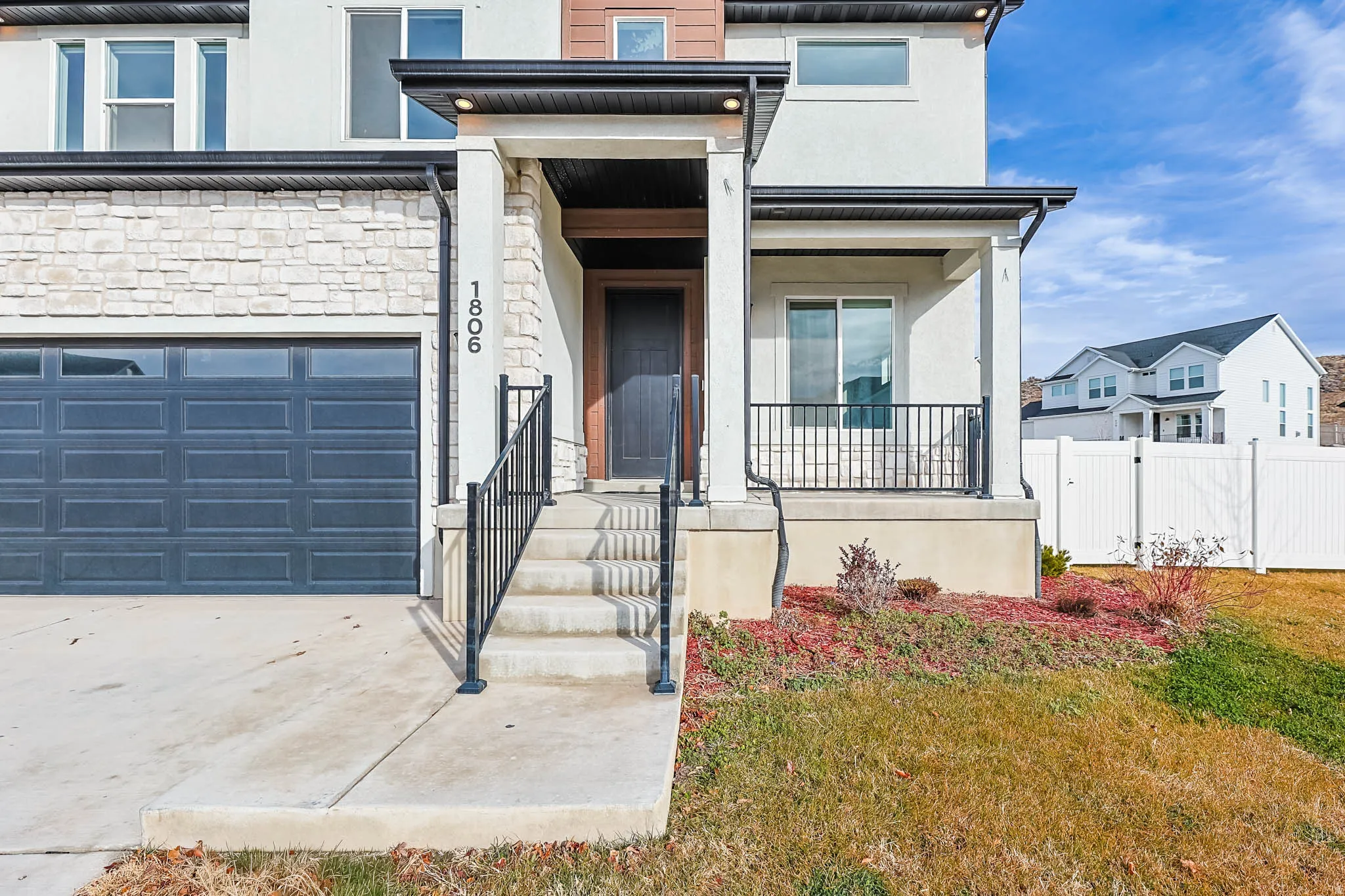 Entrance to property featuring stucco siding, a porch, stone siding, and driveway
