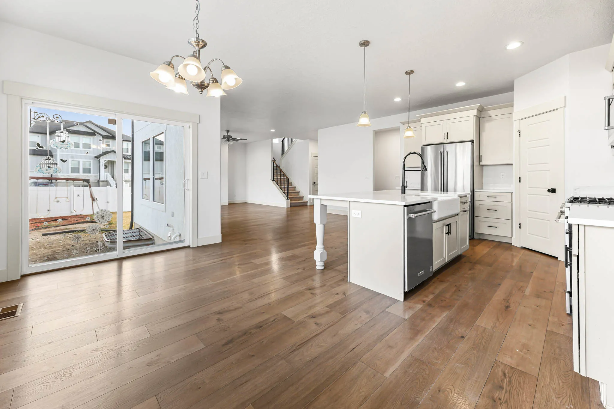 Kitchen featuring decorative light fixtures, open floor plan, an island with sink, light wood finished floors, and a chandelier