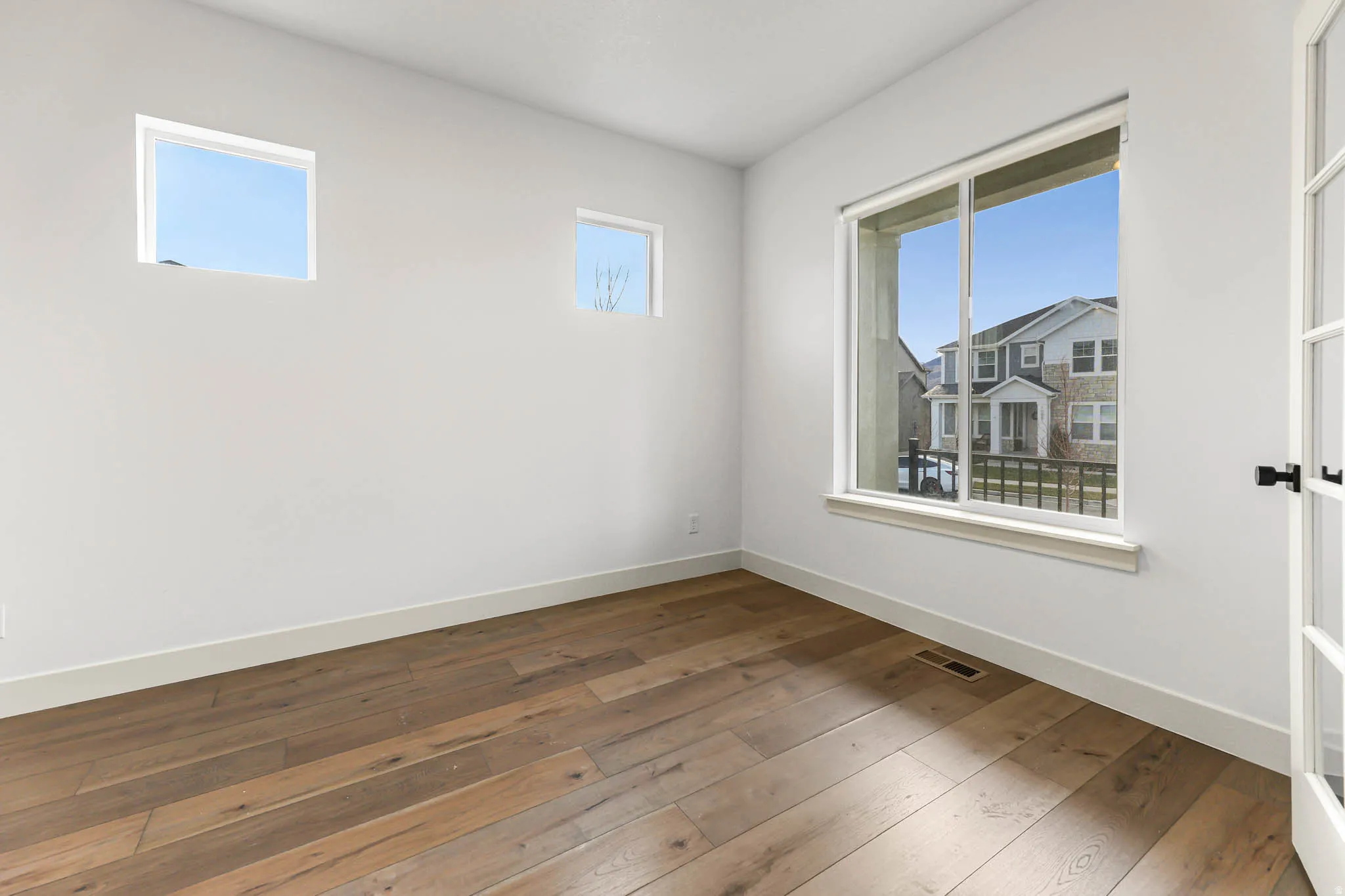 Spare room featuring plenty of natural light and dark wood-style flooring