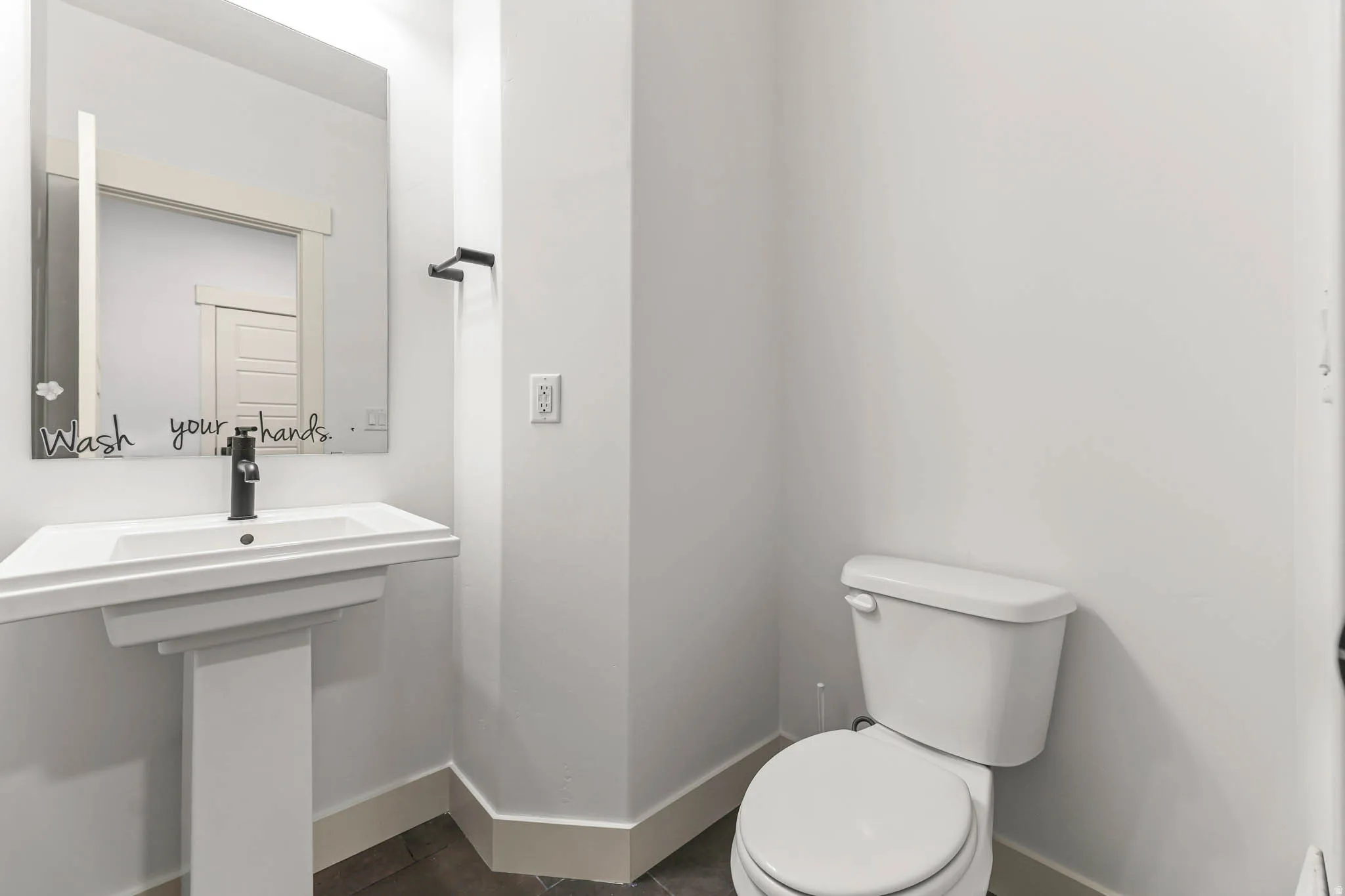 Half bath with toilet and dark tile patterned floors