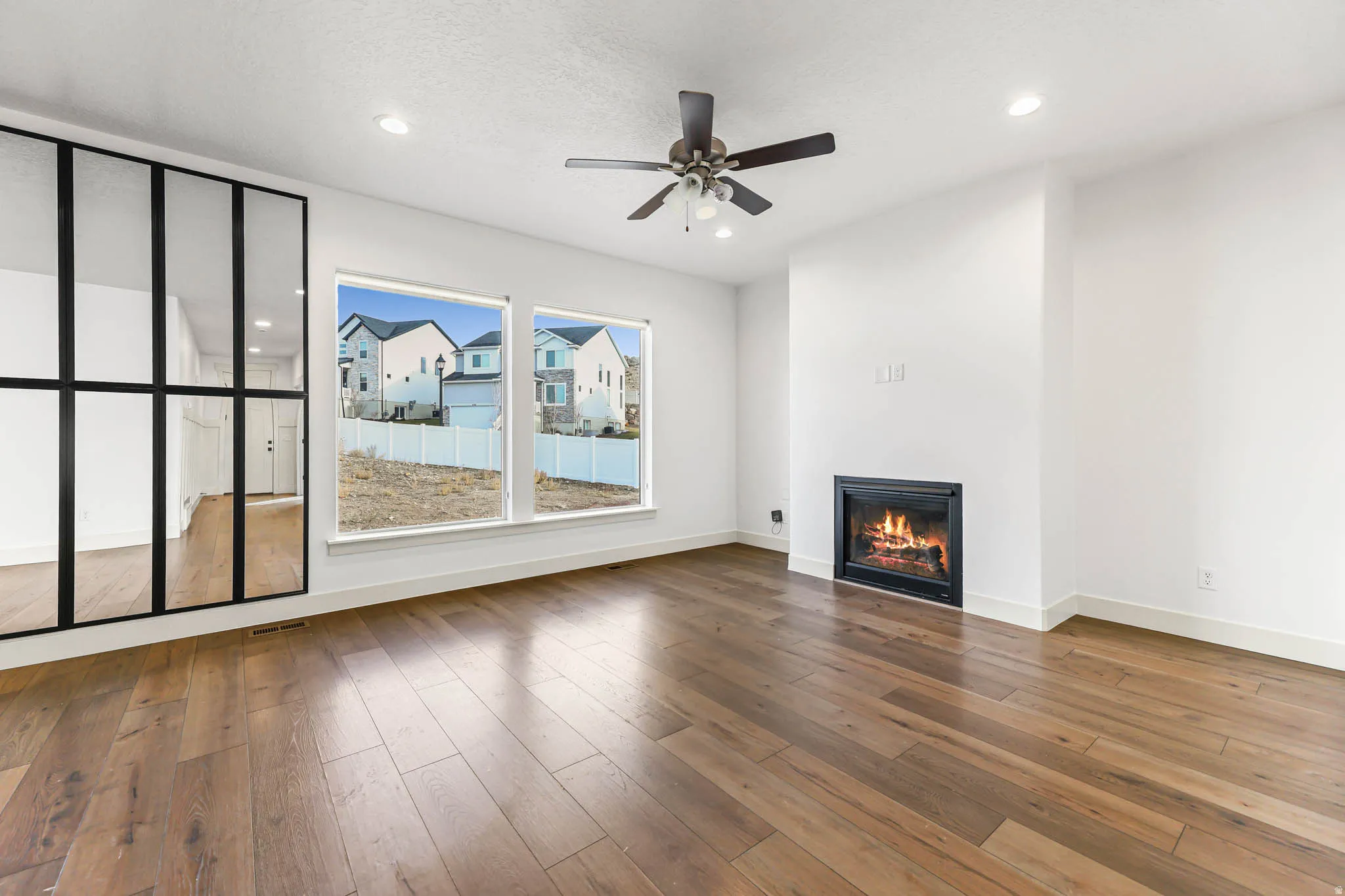 Unfurnished living room with a glass covered fireplace, hardwood / wood-style flooring, recessed lighting, and ceiling fan