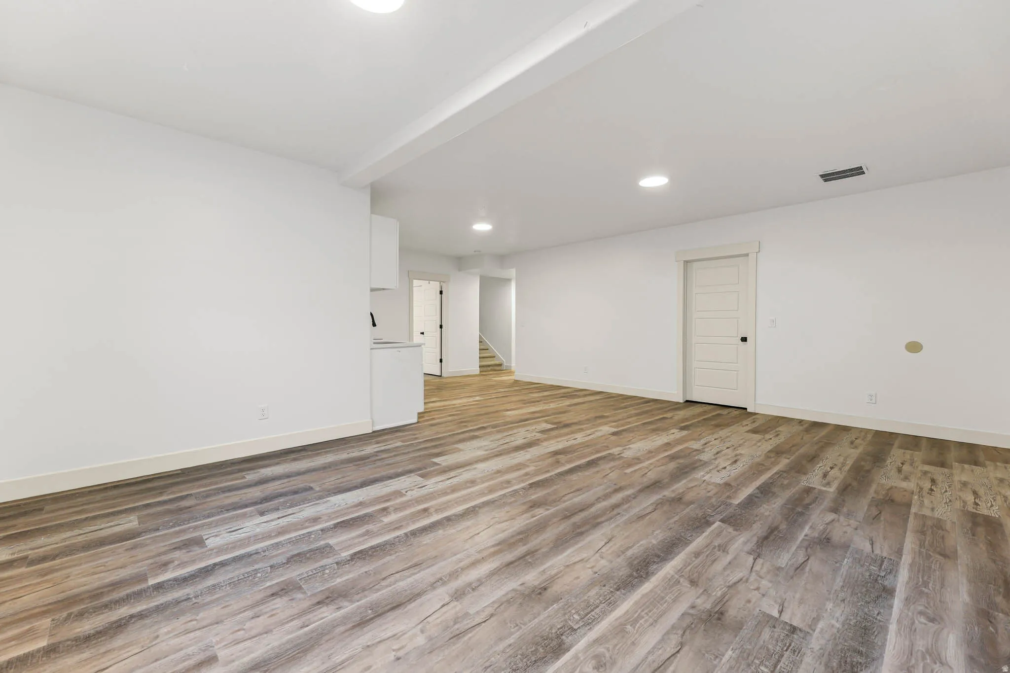 Spare room with recessed lighting, light wood-style floors, and stairway