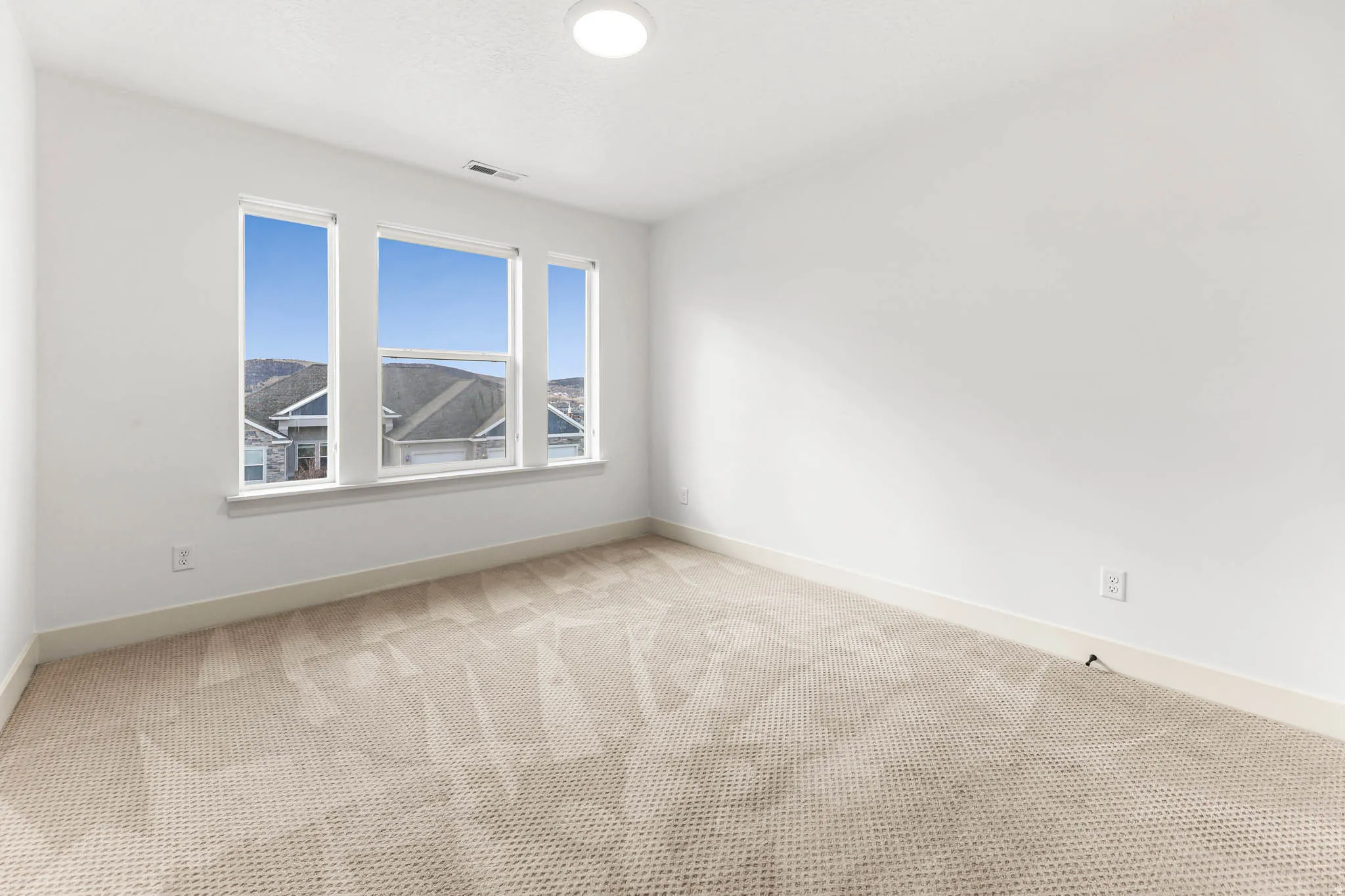 Empty room featuring baseboards and light colored carpet