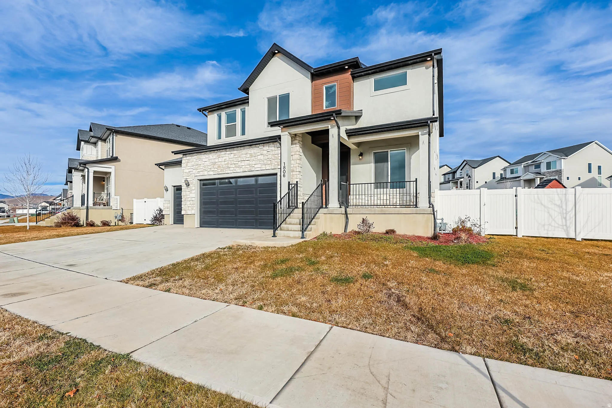 View of front of home with stucco siding, stone siding, a garage, and driveway