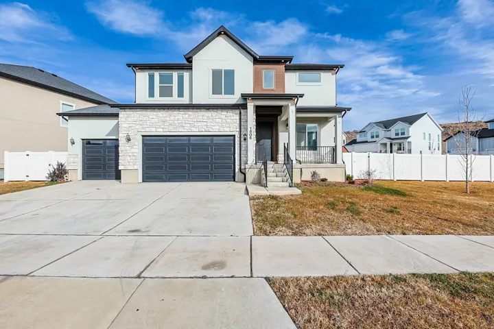 View of front of property with stucco siding, stone siding, driveway, a garage, and covered porch