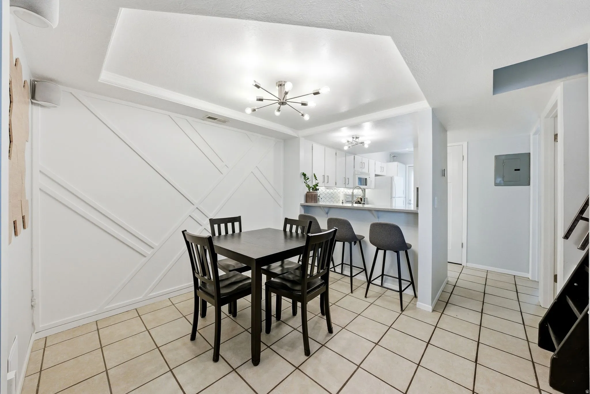 Dining room featuring a chandelier, electric panel, light tile patterned flooring, and a decorative wall