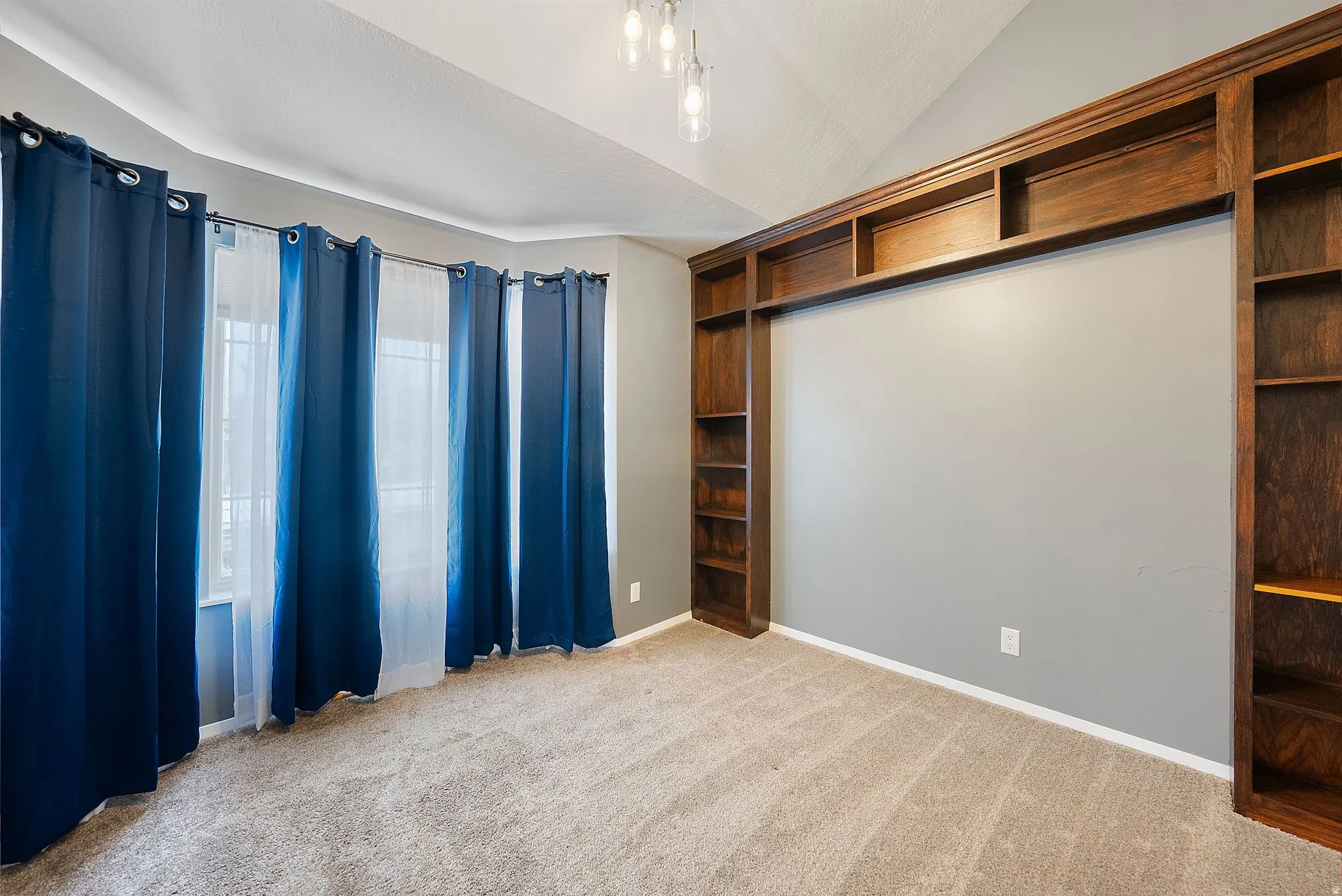 Unfurnished bedroom with lofted ceiling and light colored carpet