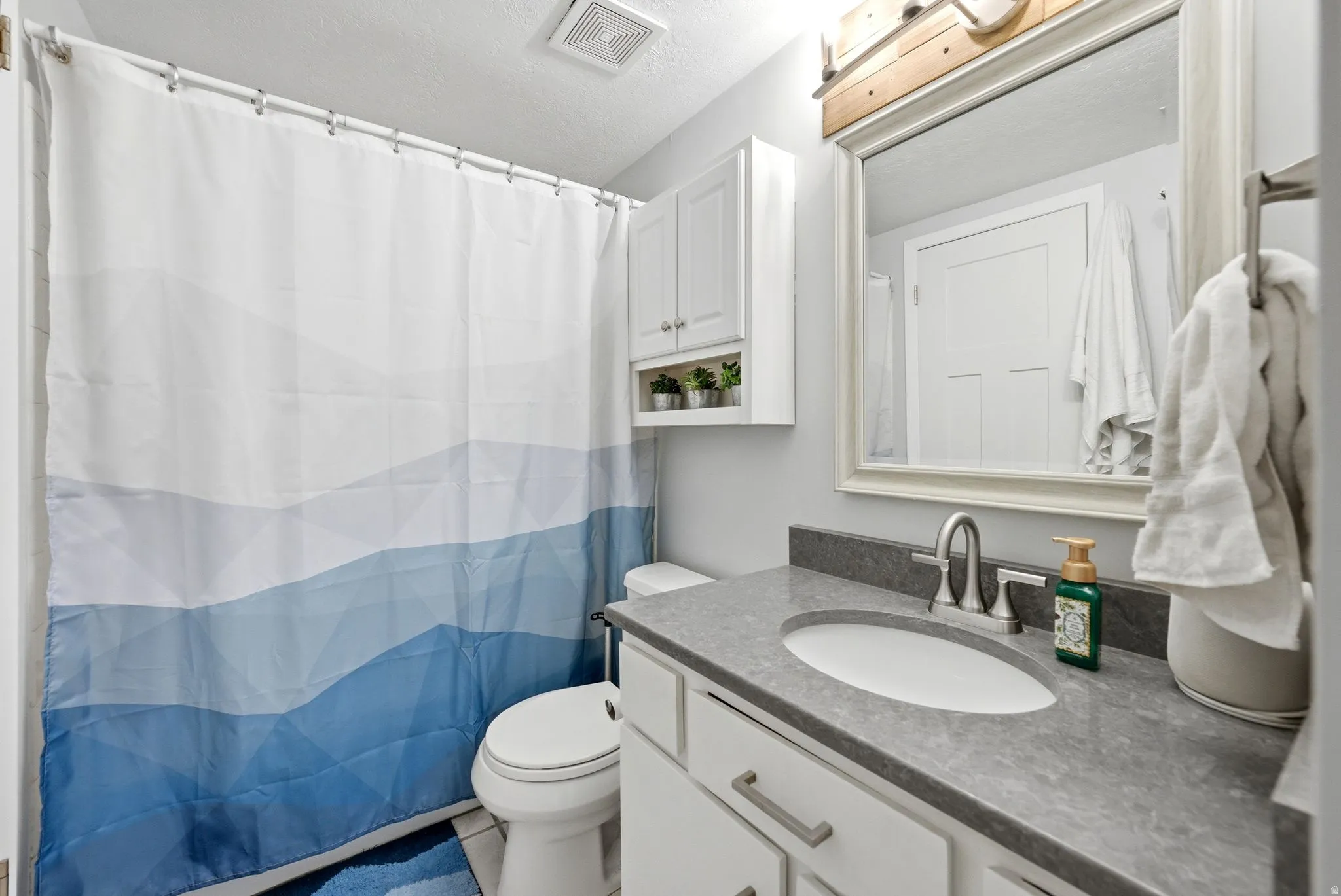 Full bath featuring a shower with curtain, vanity, a textured ceiling, and tile patterned floors