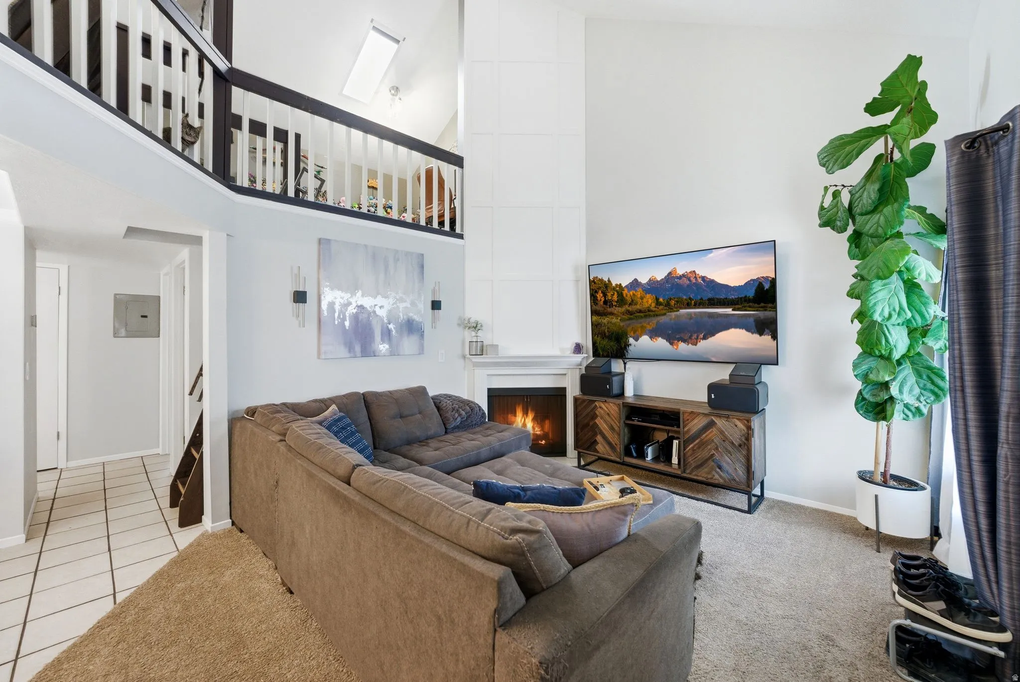 Living area featuring a high ceiling, a large fireplace, and electric panel