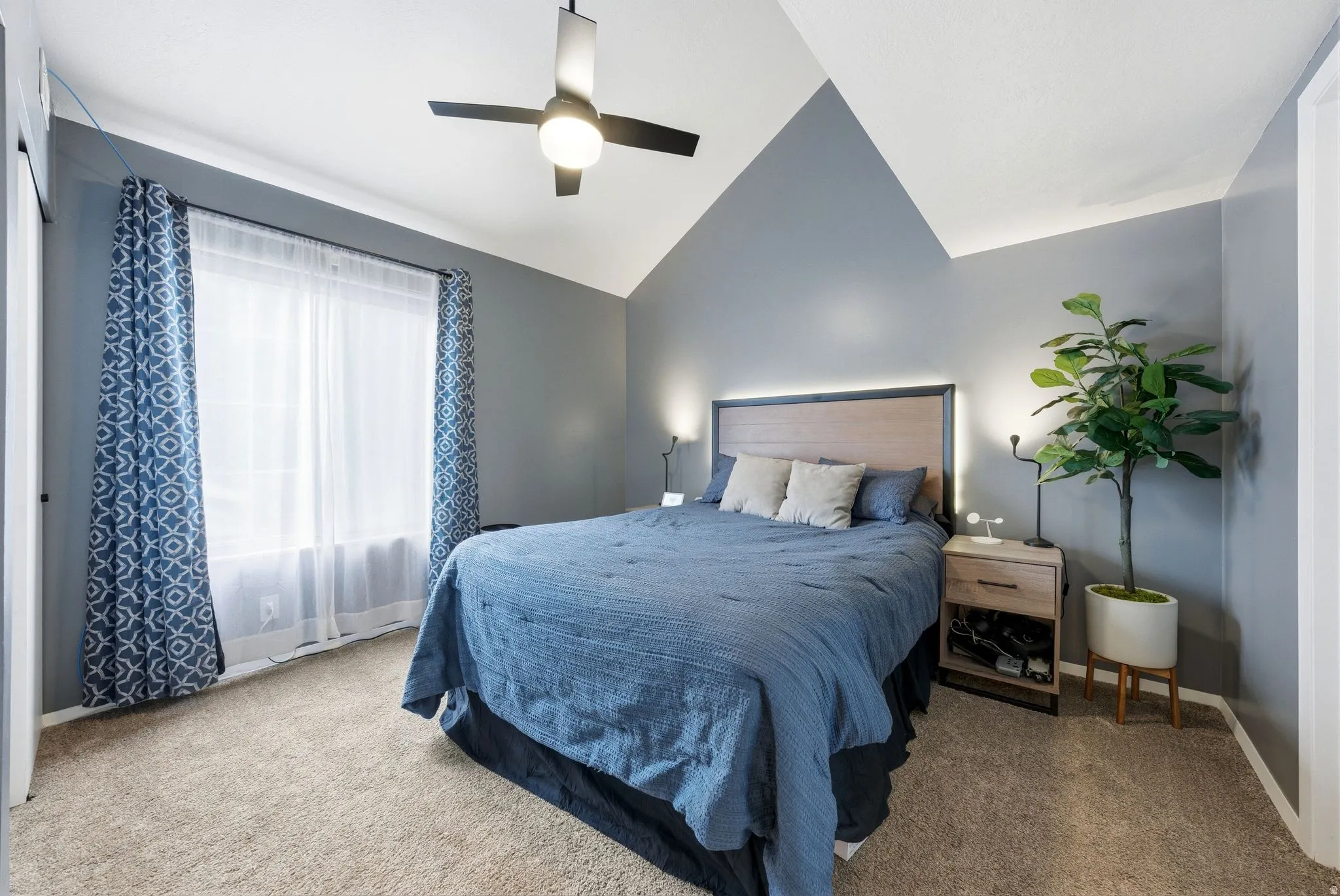 Carpeted bedroom with lofted ceiling and ceiling fan