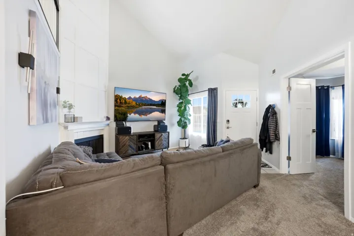 Living room with a fireplace, light colored carpet, and high vaulted ceiling