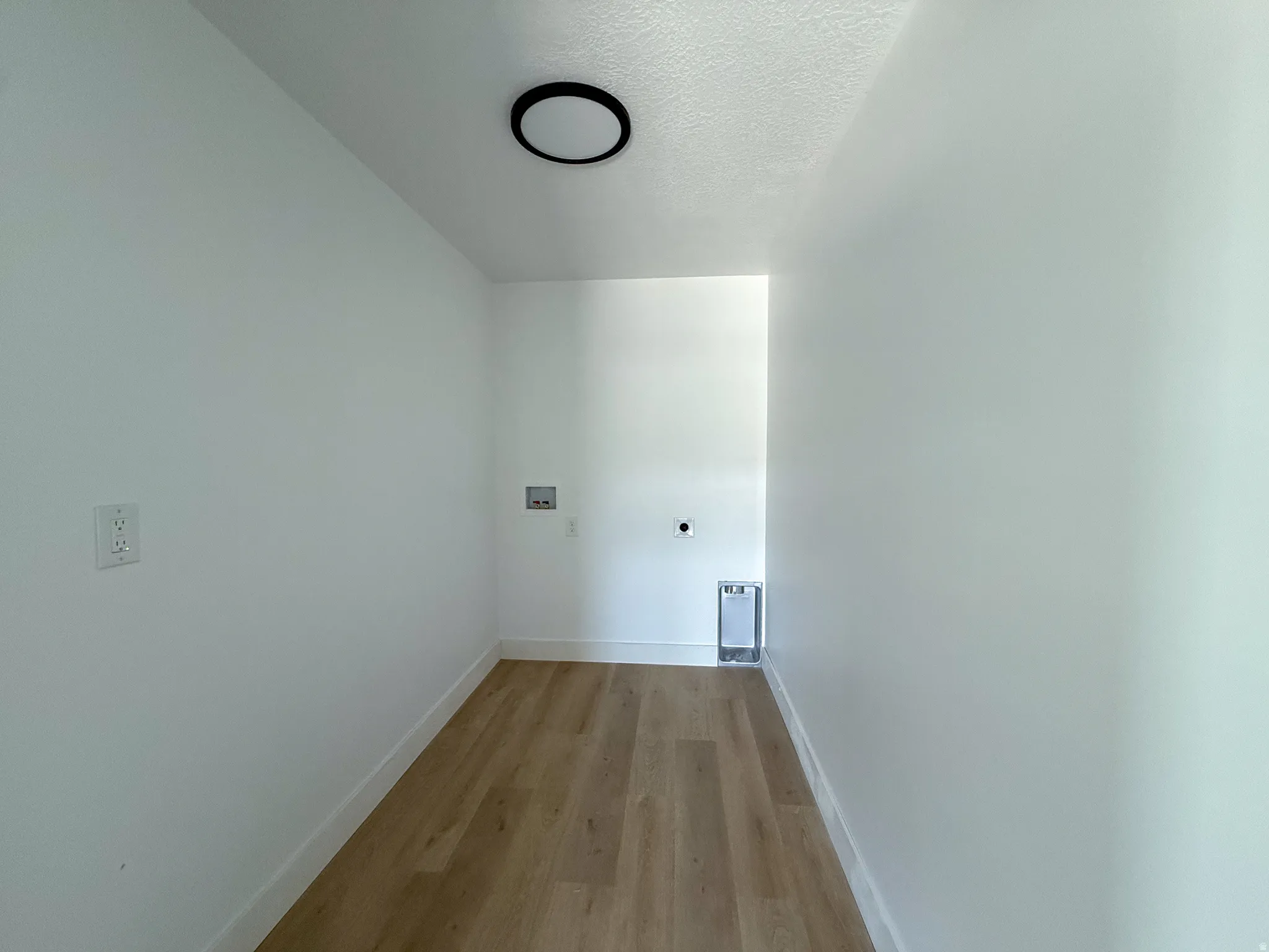 Laundry area featuring a textured ceiling, light wood finished floors, hookup for an electric dryer, and washer hookup