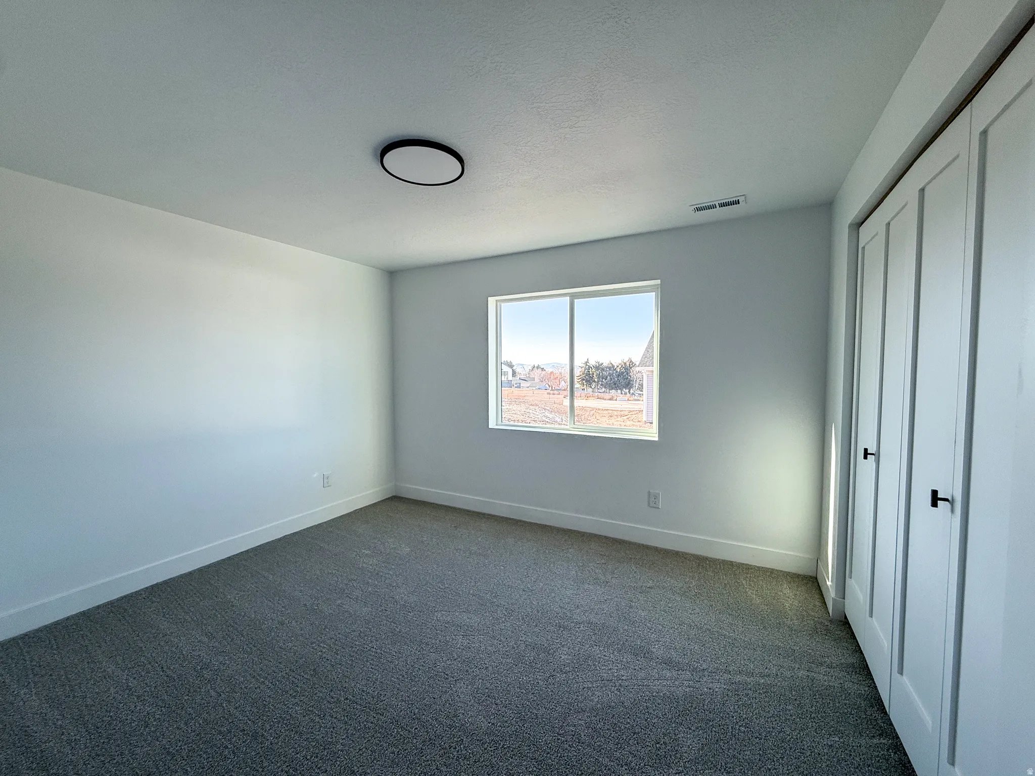 Unfurnished bedroom with a closet, dark carpet, and a textured ceiling