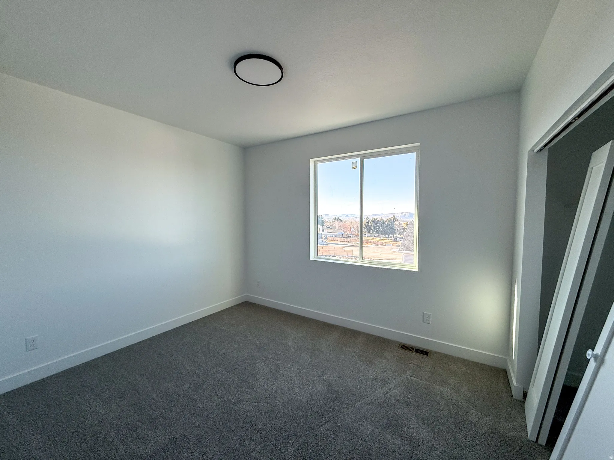 Empty room with dark colored carpet and baseboards