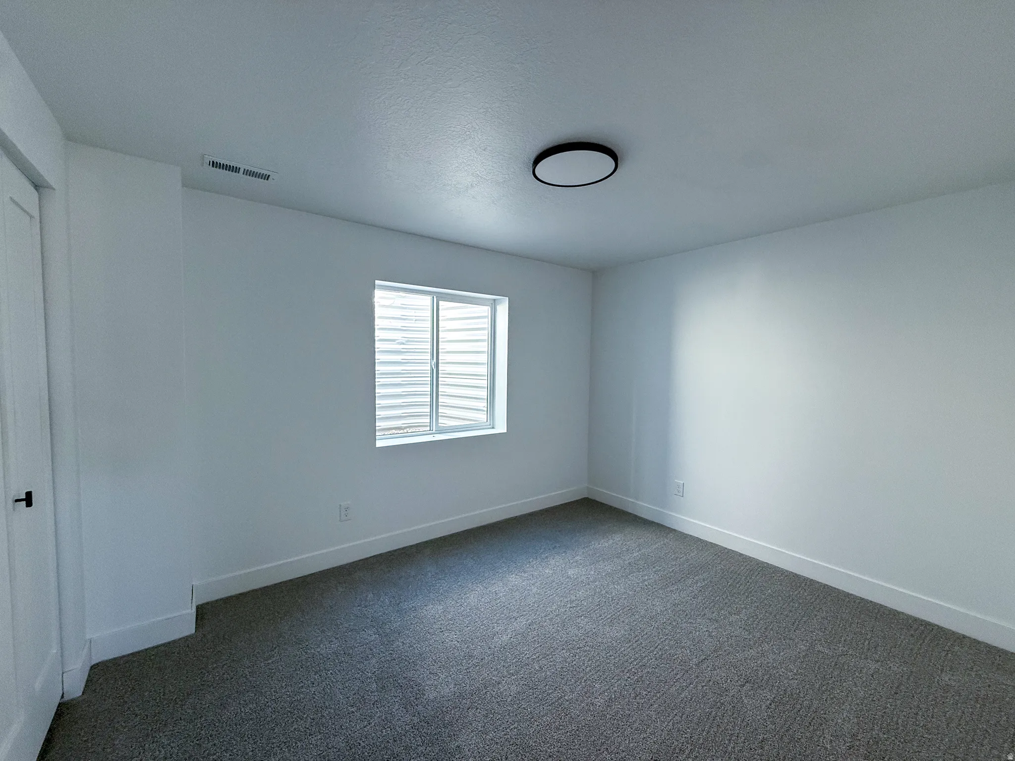 Spare room with dark carpet and a textured ceiling