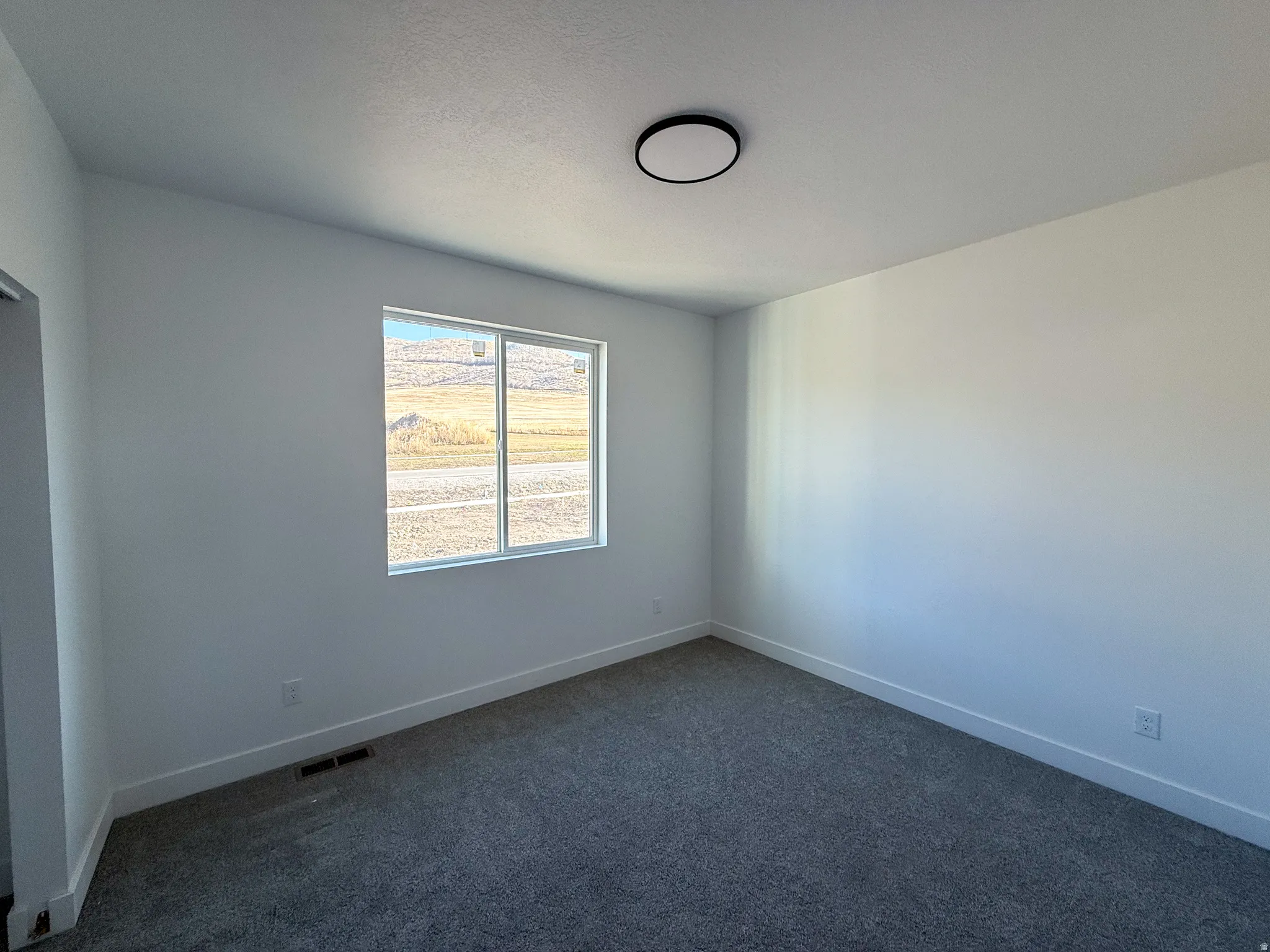 Spare room featuring dark carpet and baseboards