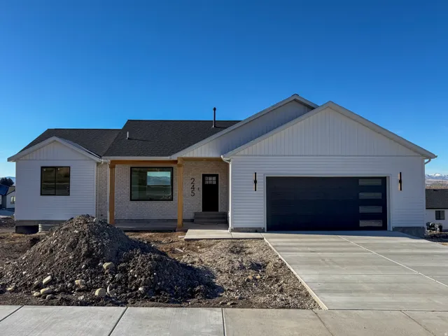 View of front facade featuring brick siding, driveway, a garage, and a shingled roof