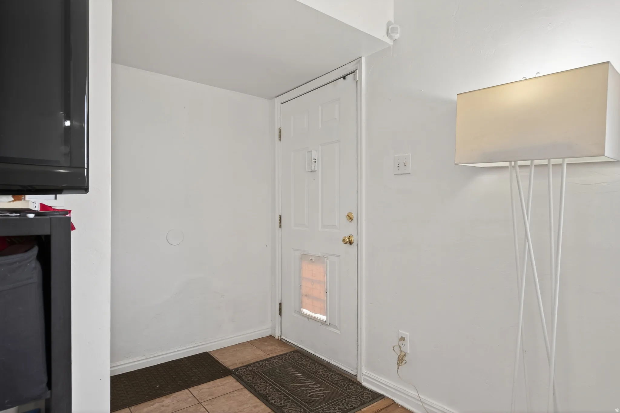 Foyer entrance with light tile patterned flooring and baseboards