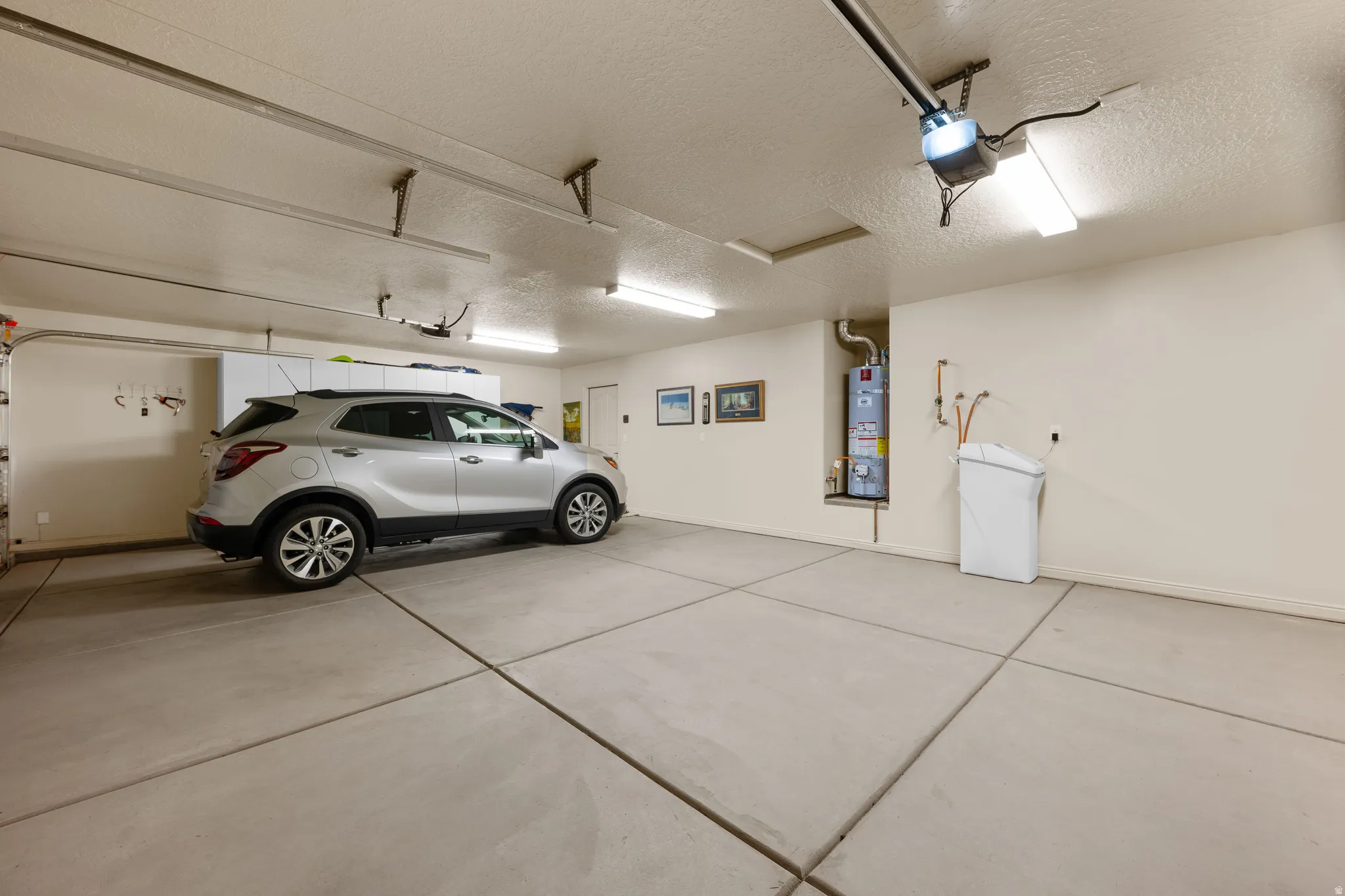 Garage featuring strapped water heater and a garage door opener
